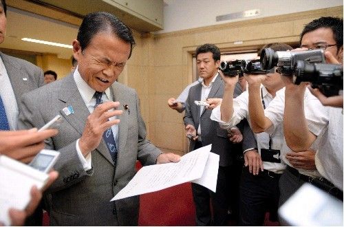 麻生太郎在记者面前照稿宣读收回言论声明。（资料图）